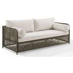 a wicker couch with white pillows on it's back and side cushions in the middle