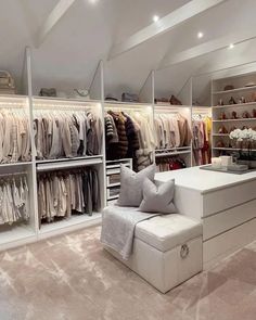 a large closet filled with lots of clothes and pillows on top of white shelving