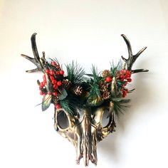 two antlers decorated with pine cones, berries and evergreen needles are mounted on the wall