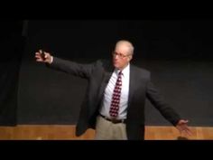 a man in a suit and tie standing on stage with his arms spread wide open