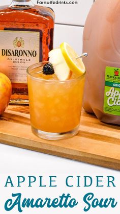 an apple cider is garnished with apples and lemons on a cutting board