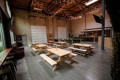 several picnic tables are set up in the middle of a large room with lights hanging from the ceiling