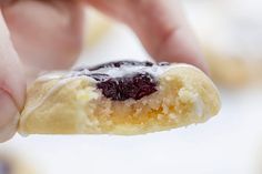 a hand holding a pastry with blueberries and icing on it's side