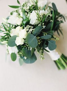 a bouquet of white flowers and greenery on a table