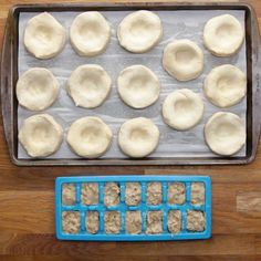 an uncooked pan filled with dumplings on top of a wooden table next to a cookie sheet