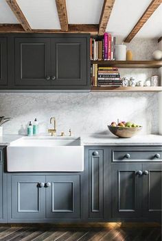 a kitchen with gray cabinets and white counter tops, wooden flooring and open shelving