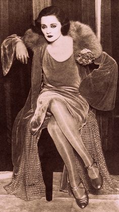 an old fashion photo of a woman sitting on a chair with her legs spread out