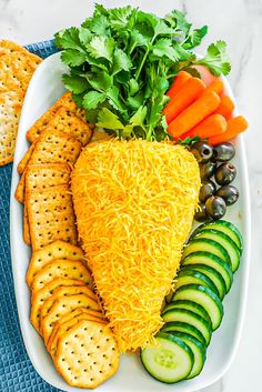 a platter with crackers, cucumbers and carrots