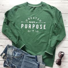 Created with A Purpose Sweatshirt | Wear this Sweater with pride knowing that a % of your purchase goes towards spreading the word of God. Part will go to building new churches, and part will go to sending missionaries around the world. Created with A Purpose Sweatshirt is not only adorable but extremely soft too! Its bold Message will be sure to turn heads! #christianapparel #womensfashion #winteroutfits #winterfashion #sweateroutfits #winteroutfits #sweater #womenssweater #valerymilano Slogan Clothing, Jesus Clothes, Womens Sweatshirts Fashion, Sweatshirt Aesthetic, Crewneck Sweatshirt Women, Graphic Print Sweatshirt, Christian Sweatshirt, Simple Tshirt, Sweatshirt Women