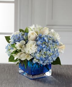 a blue vase filled with white and blue flowers