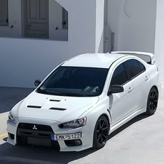 a white car parked in front of a building with no one on the ground around it