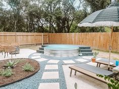 a patio with an outdoor hot tub and lounge chairs in the back yard, next to a wooden fence