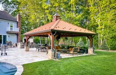 a gazebo sitting on top of a lush green field next to a swimming pool