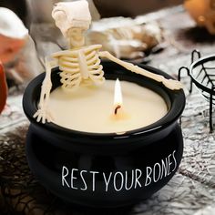 a candle with a skeleton in it sitting on a table next to other halloween decorations