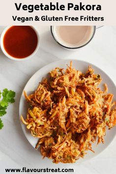 a white plate topped with fried vegetables next to a cup of tea and sauces