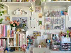 a cluttered desk with lots of books and pictures on the wall next to it