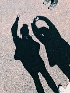 two people standing next to each other with their shadow cast on the ground in front of them