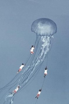 several people are flying in the sky with a jellyfish