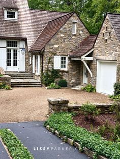 a large stone house with white doors and windows on the front door is surrounded by greenery