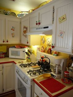 a small kitchen with white cabinets and red counter tops, including a stove top oven