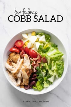 a white bowl filled with chicken, lettuce and tomatoes on top of a marble counter