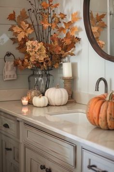 a bathroom counter with candles and pumpkins on it