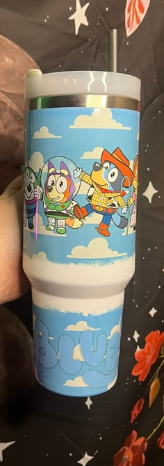 a person holding a cup with cartoon characters on it