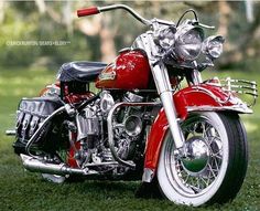 a red motorcycle parked on top of a lush green field