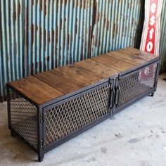 a metal and wood bench sitting in front of a rusty wall