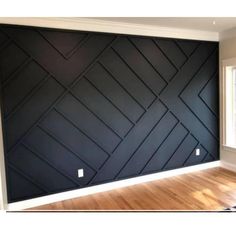 an empty room with black walls and wood floors