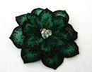 a green flower brooch sitting on top of a white surface