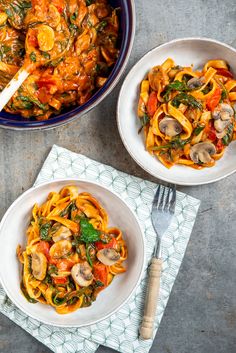 two bowls of pasta with mushrooms, spinach and tomato sauce next to a fork