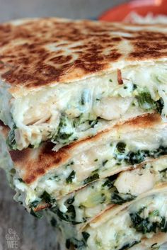 a stack of quesadillas stacked on top of each other with cheese and spinach