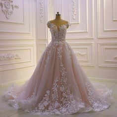 a wedding dress is displayed on a mannequin in front of a white wall