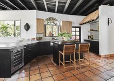 a kitchen with black cabinets and tile flooring next to an island in the middle