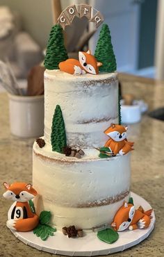 a three tiered cake decorated with foxes and pine trees