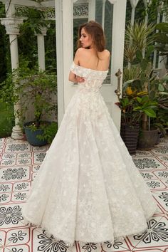 a woman in a white wedding dress standing on a tiled floor with her back to the camera