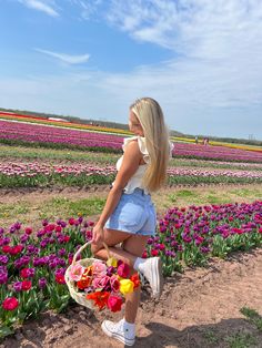 a woman kneeling down in front of a field full of flowers