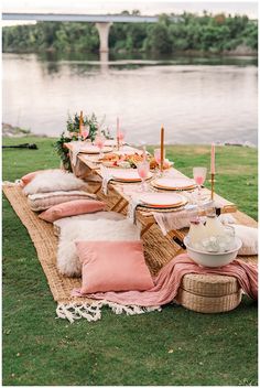 a table set up with pink and white pillows, plates and utensils on it