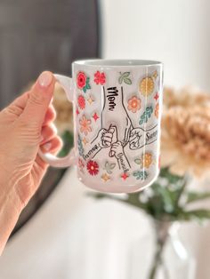 a person holding a coffee mug with flowers on it