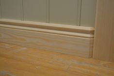 the corner of a room with wood flooring and white paint on the door frame