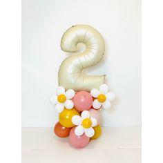 the number two balloon is on top of some balloons in front of a white wall