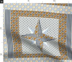 an orange and blue quilt with white flowers on the center is being measured by a ruler