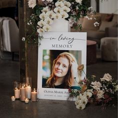 a memorial sign with flowers and candles next to it