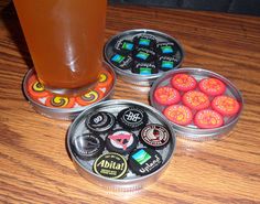 three tins with different types of buttons on them and a drink in the background