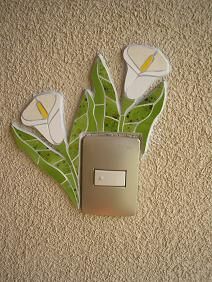 a light switch cover with flowers and leaves on the wall in front of carpeted floor