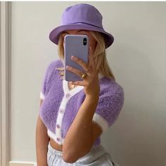 a woman wearing a purple hat and sweater taking a selfie with her cell phone