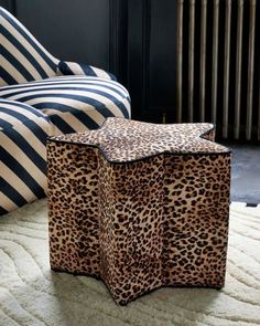 a cheetah print box sitting on top of a rug next to a chair