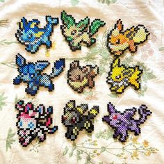 nine pixelated pokemon brooches sitting on top of a white cloth covered table