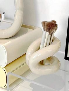 three brushes are sitting in a holder on the counter next to a mirror and soap dispenser